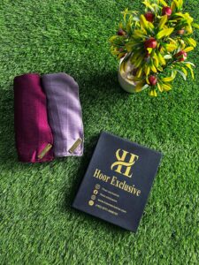 Pack of two premium silk satin hijabs in maroon and lavender shades with Hoor Exclusive packaging on grass background
